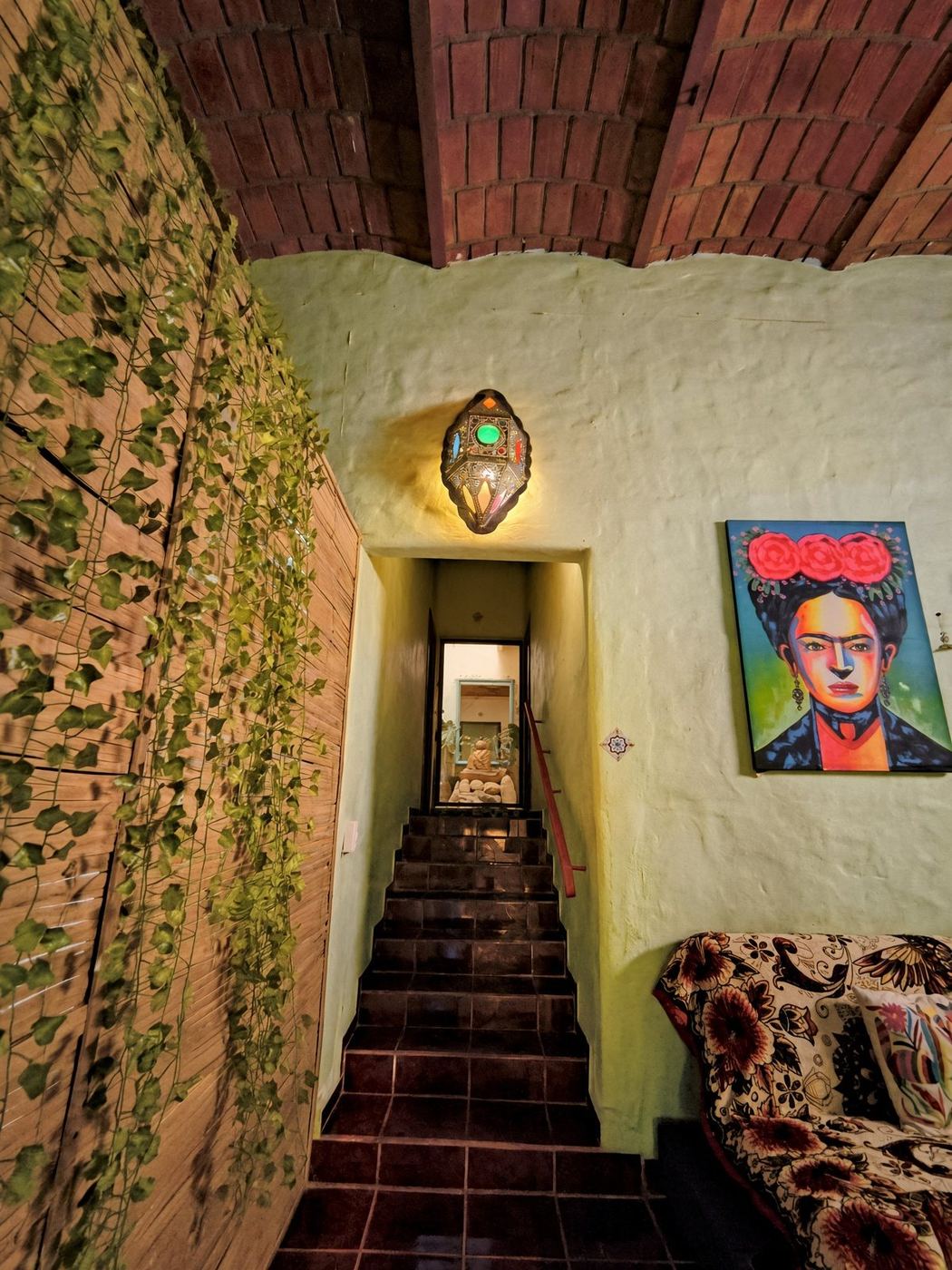 Stairs at La Casa Grande, ivy on the wood screen, a glowing lantern, and the courtyard below