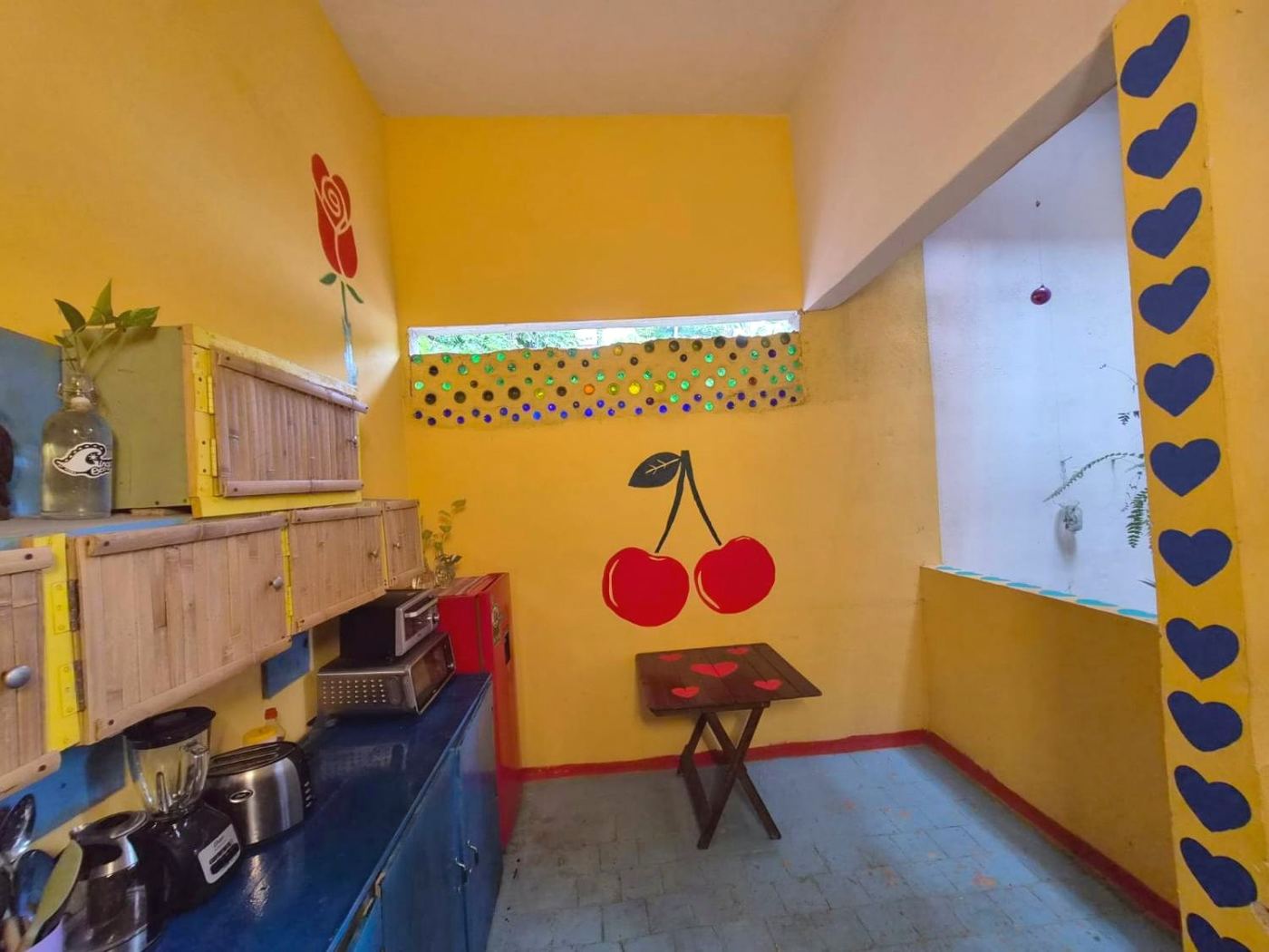 Cherries painted on the kitchen wall at Two bedroom Delight, with a heart-dotted table
