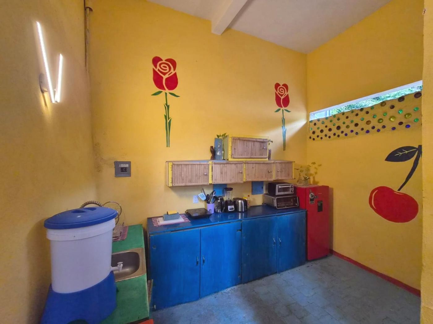 The kitchen at Two bedroom Delight, yellow walls, painted roses, and blue cabinets