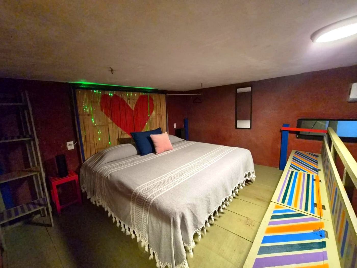 The loft bed at Two bedroom Delight, a red heart on bamboo and a striped railing