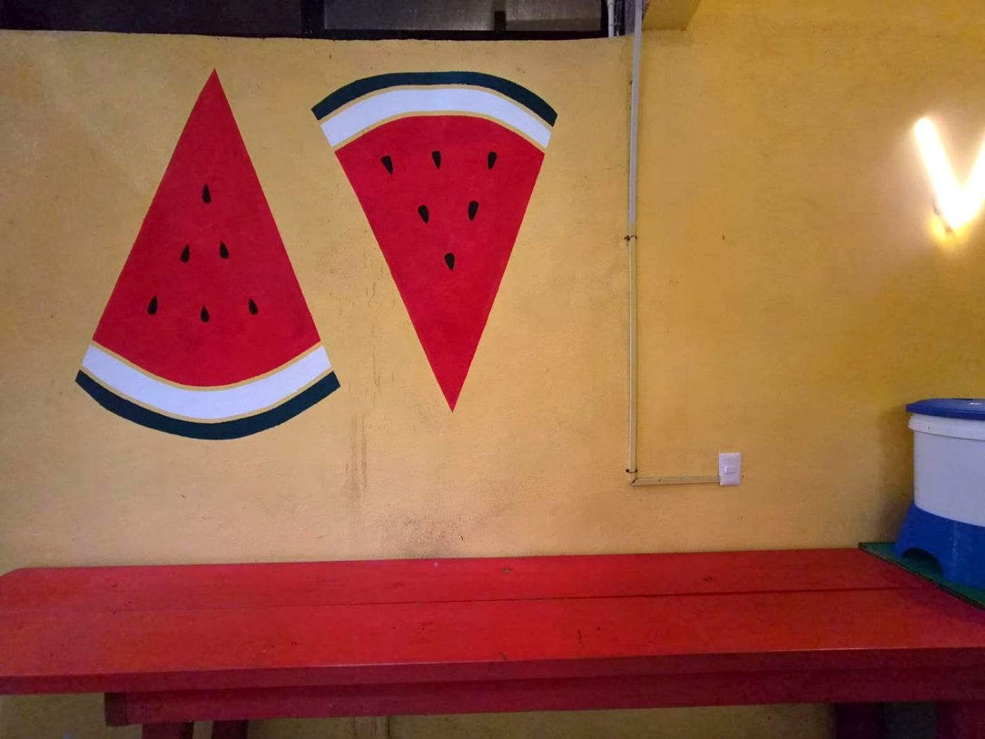 Two painted watermelon slices above the red table at Two bedroom Delight