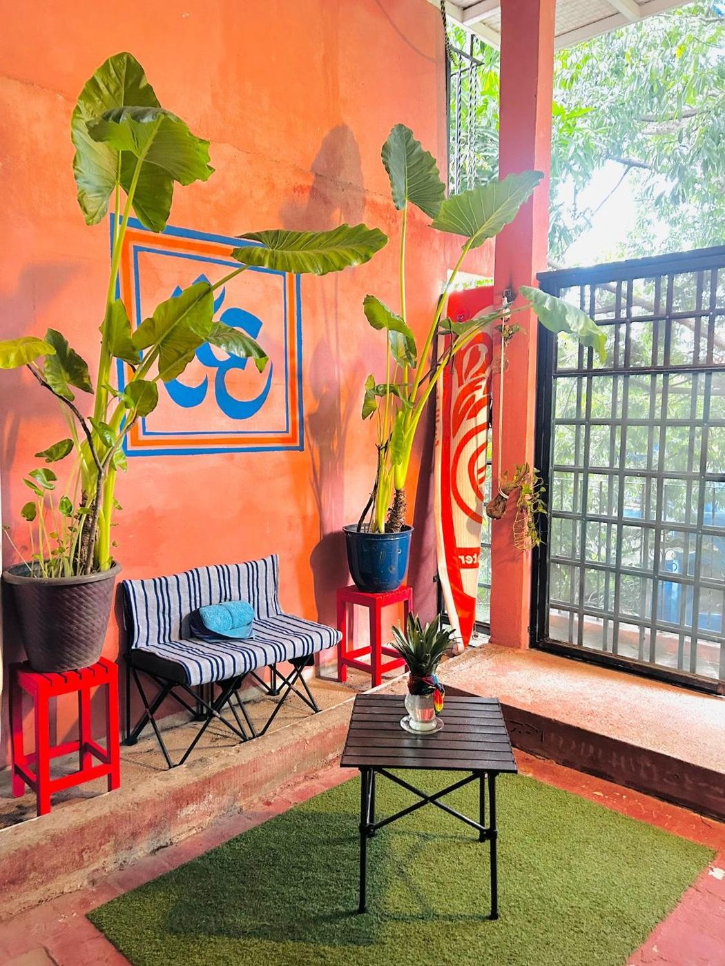 Orange wall at El Loft, a blue Om, elephant ears, and a striped bench