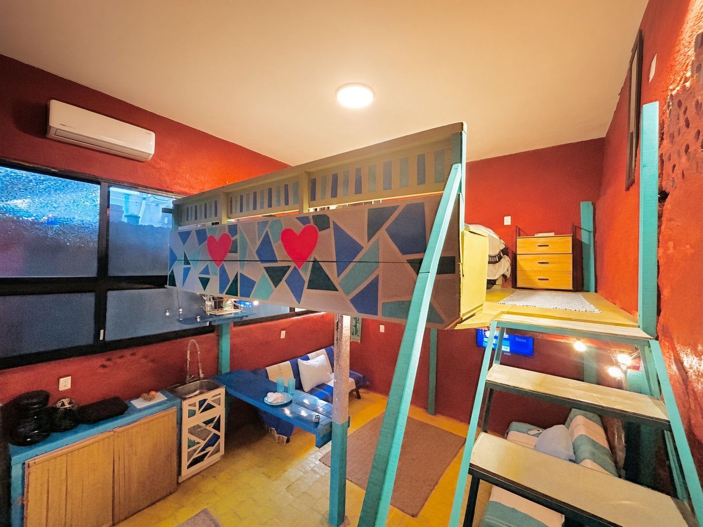 El Loft from above, a geometric railing with pink hearts, yellow tile, and the kitchen below