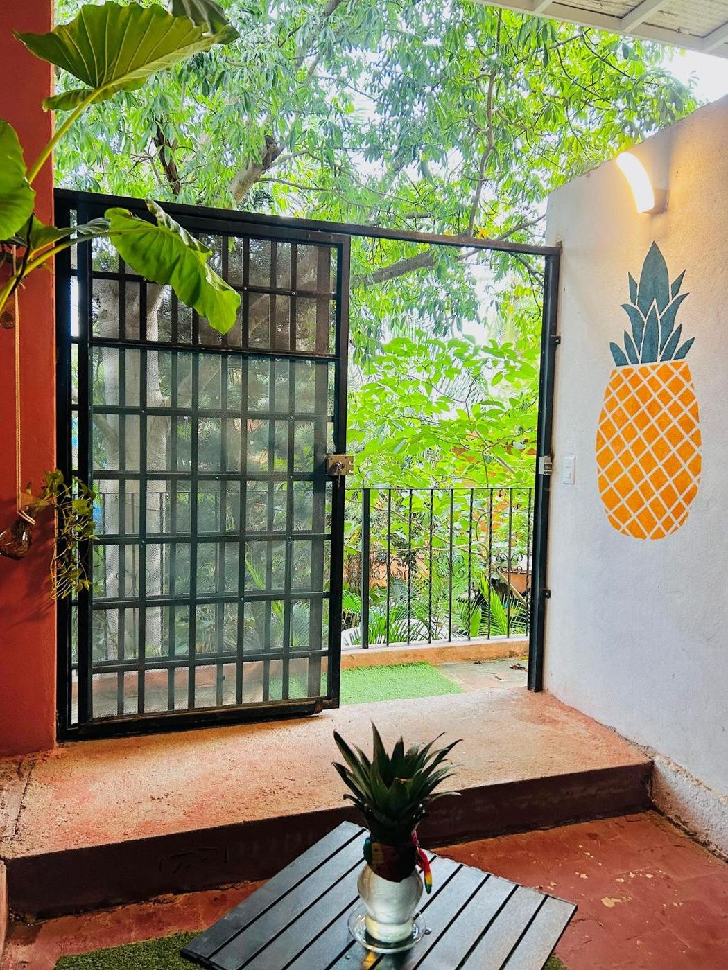 A small pineapple in a glass jar on the black table by the gate
