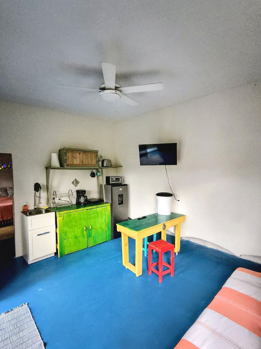 The kitchen at Casita Sol, green cabinets, a small fridge, and the sofa bed