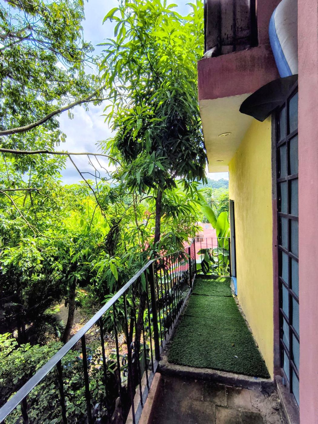 The long balcony at Casita Sol, a strip of turf and the trees beyond the rail